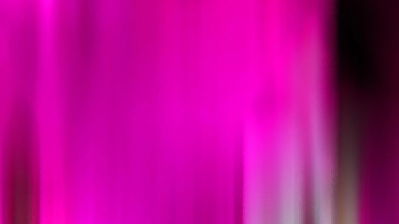 Vertikal verwischte Streifen in Magenta und Pink, rechts ein dunkler Rand und helle Schlieren am unteren Bildrand.