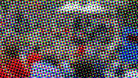 Dichtes Raster aus kleinen, farbigen Punkten in Rot, Grün, Blau, Gelb und Cyan, durchsetzt von schwarzen Punkten, die in der Mitte und unten rechts eine dunkle Fläche bilden.