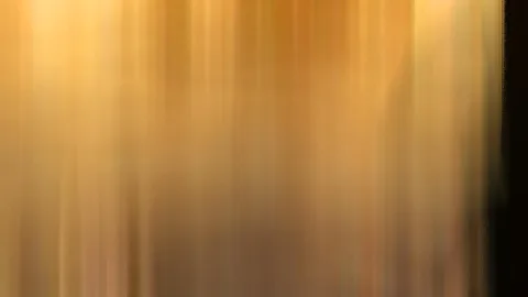 Vertikal verwischte Streifen in Gold und Orange, rechts ein dunkler Rand.
