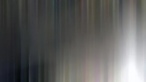 Vertikal verwischte graue Schlieren, links dunkel, rechts hell leuchtend.