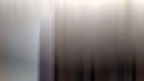 Abstrakte, vertikal verwischte Streifen in Grau, Weiß und Braun, links heller, rechts dunkler.