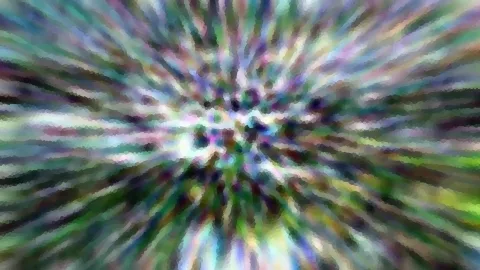 Abstrakte Aufnahme mit radialer Bewegungsunschärfe. Von einem dunklen Zentrum aus strahlen grüne, violette und weiße Streifen nach außen, das Bild ist mosaikartig gepixelt.