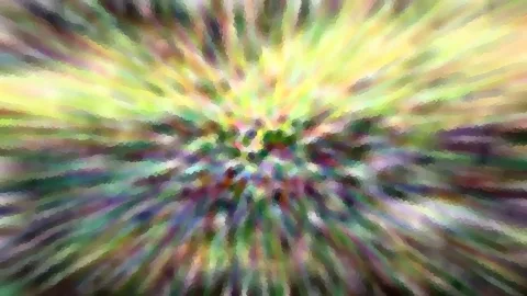 Abstrakte Komposition aus gelben, grünen und violetten Farbstrahlen, die von der Bildmitte radial nach außen laufen, grob gepixelt.