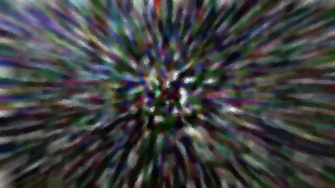 Abstrakte radiale Unschärfe mit grünen, violetten und weißen Farbstreifen, die von einem dunklen Zentrum nach außen laufen.