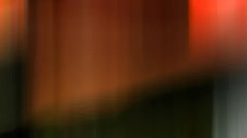 Verschwommene vertikale Streifen in Orange und Braun, rechts oben ein helles Rot, unten dunkles Grün.