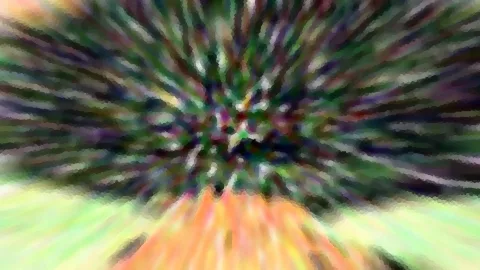 Abstrakte Unschärfe mit radial von der Mitte nach außen laufenden Streifen in Grün, Lila und Weiß, unten orangefarbene Schlieren.