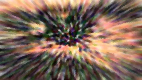 Abstrakte Komposition aus radial verwischten Farbstreifen in Orange, Grün und Violett, die von einer dunkleren Mitte nach außen strahlen.