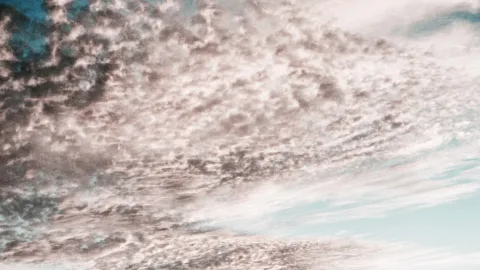 Feine, aufgewühlte Wolkenschichten ziehen diagonal über den Himmel, oben links und rechts blitzt kühles Blau durch.