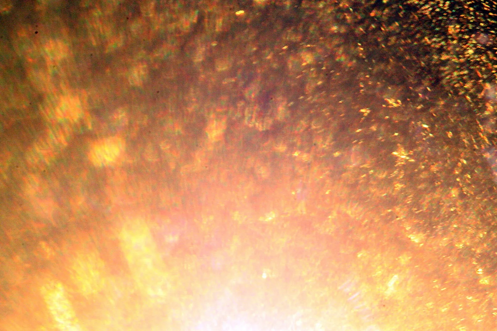 Nahaufnahme einer glitzernden Oberfläche in Orange und Gold, oben dunkler, unten zur Mitte hin hell ausgeleuchtet.