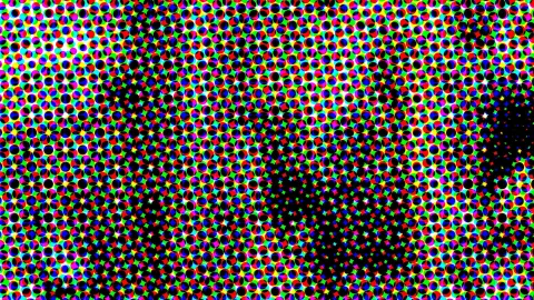 Dichtes Raster aus kleinen farbigen Punkten in Rot, Grün, Blau, Gelb und Magenta auf schwarzem Grund, im Zentrum und rechts unten verdichtet sich das Schwarz zu einem diagonalen Band.