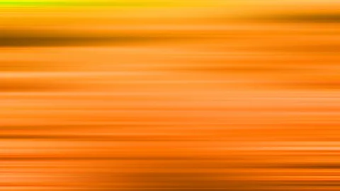 Abstrakte Fläche aus horizontalen, verwischten Streifen in Orange, Gelb und Braun, oben ein grüner Lichtstreifen am Rand.