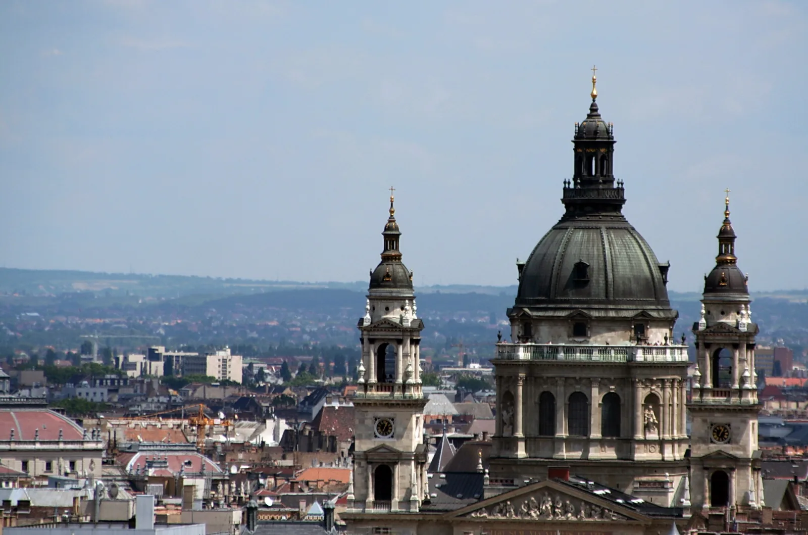 Blick über Budapester Dächer auf die Kuppel und die beiden Glockentürme der Szent-István-Basilika unter hellblauem Himmel
