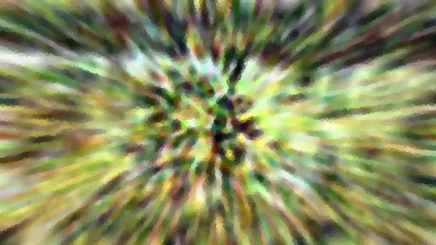 Radial verwischte Aufnahme von grünem und gelbem Laub mit mosaikartiger Pixelstruktur, Bildmitte dunkler.