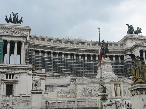 Weißes Monument mit Säulenreihen, Reiterstatue und Quadriga unter bewölktem Himmel in Rom