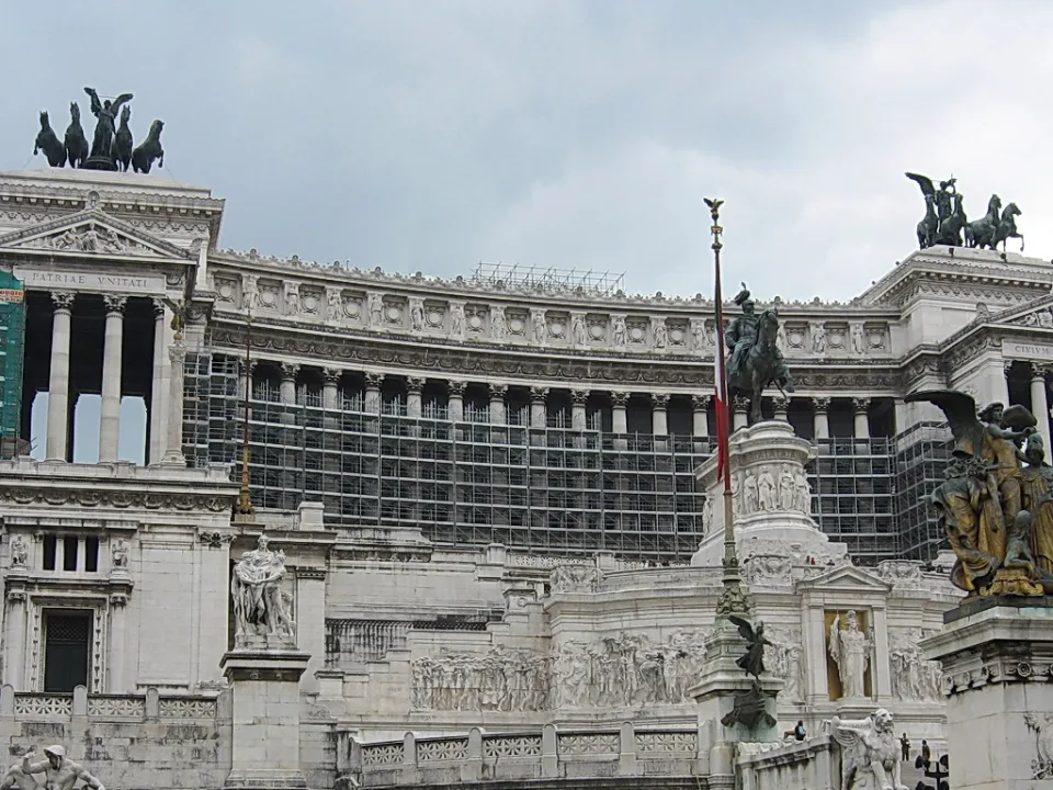 Weißes Monument mit Säulenreihen, Reiterstatue und Quadriga unter bewölktem Himmel in Rom
