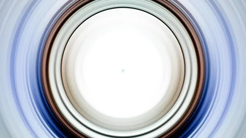Abstrakte Komposition aus konzentrischen Ringen in Braun, Grau und Blau, radial verwischt, mit hellem weißem Zentrum.