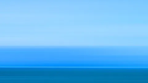 Horizontal verwischte Bahnen in Blau- und Türkistönen; oben hellblauer Himmel, darunter ein dunkleres Blau mit einer hellen Linie am Horizont und einer dunkleren Fläche am unteren Rand.