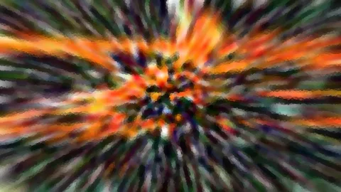 Abstrakte Radialunschärfe mit orangefarbenen, grünen und violetten Streifen, die von einem dunklen Zentrum nach außen strahlen.