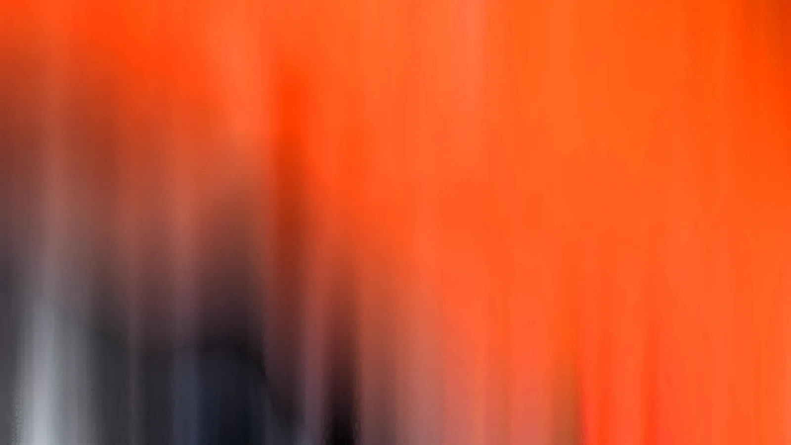 Verwischte vertikale Schlieren in Orange, links unten dunkles Grau und helles Weiß.