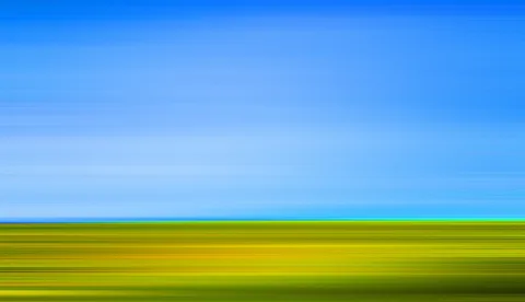 Abstrakte Aufnahme mit horizontalen Streifen: oben ein kräftiges Blau des Himmels, unten gelbgrüne Wiese, getrennt durch eine schmale Horizontlinie.