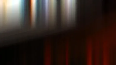 Vertikal verwischte Lichtstreifen in Weiß, Blau und Rot auf dunklem Grund.