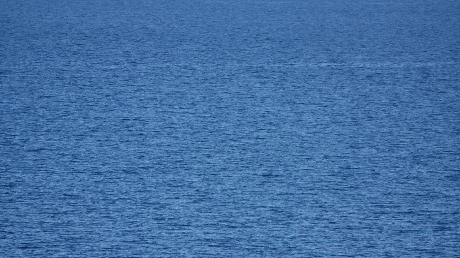 Tiefblaue Wasseroberfläche mit feinen Wellen und leichtem Glitzern, ohne sichtbaren Horizont.