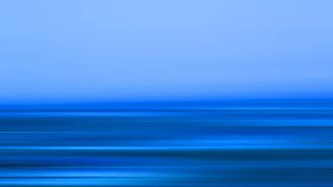 Horizontale, verwischte Linien in verschiedenen Blautönen. Oben ein heller, nahezu gleichmäßiger Himmelsverlauf, unten dichte, horizontale Streifen wie bei einer Bewegungsunschärfe.