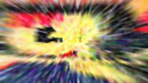 Abstraktes, radial verwischtes Bild mit gelben, roten und grünen Farbstrahlen um einen hellen Mittelpunkt, unten dunkelblaue Streifen.
