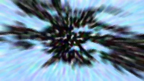 Abstrakte Aufnahme mit radialem Zoomeffekt: dunkle Zweige strahlen aus einem Zentrum vor hellblauem Himmel.