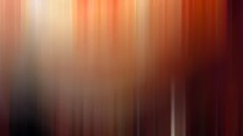 Abstrakte vertikale Bewegungsunschärfe in Orange, Rot und Braun mit hellem Licht oben links.