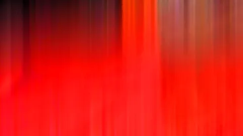 Abstrakte, vertikal verwischte Streifen in Rot und Orange, oben links in Schwarz übergehend.