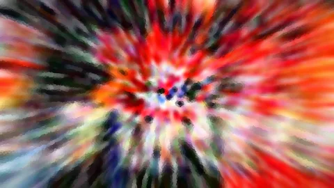 Abstraktes Bild mit radialer Unschärfe: rote, orange, grüne und blaue Farbschlieren laufen von einem hellen Zentrum mit dunklen Punkten nach außen.