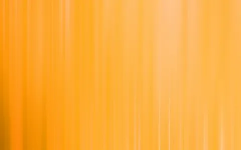 Vertikale, weich verwischte Streifen in Gelb und Orange, die von oben nach unten verlaufen und nach rechts heller werden.