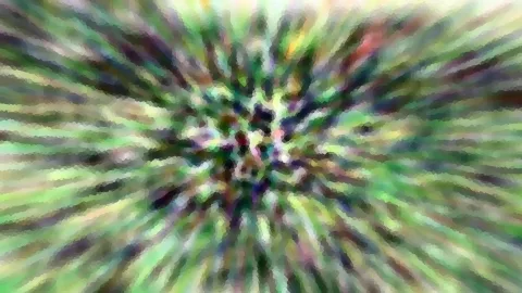 Radial verwischte Farbstreifen in Grün, Violett und Weiß, die von einem hellen Zentrum nach außen laufen.