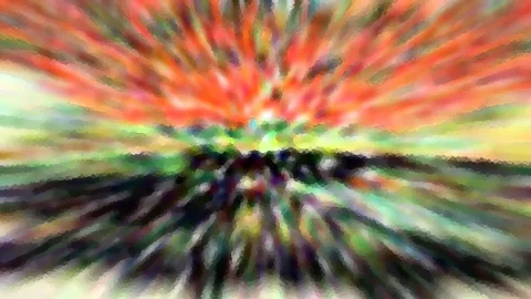 Abstrakte Zoomunschärfe mit radialen Streifen in Rot, Orange, Grün und Schwarz, die von einem hellen Zentrum am oberen Bildrand nach außen strahlen.