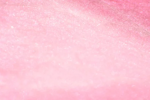 Nahaufnahme einer rosafarbenen Blüte mit feiner, glitzernder Oberflächenstruktur.