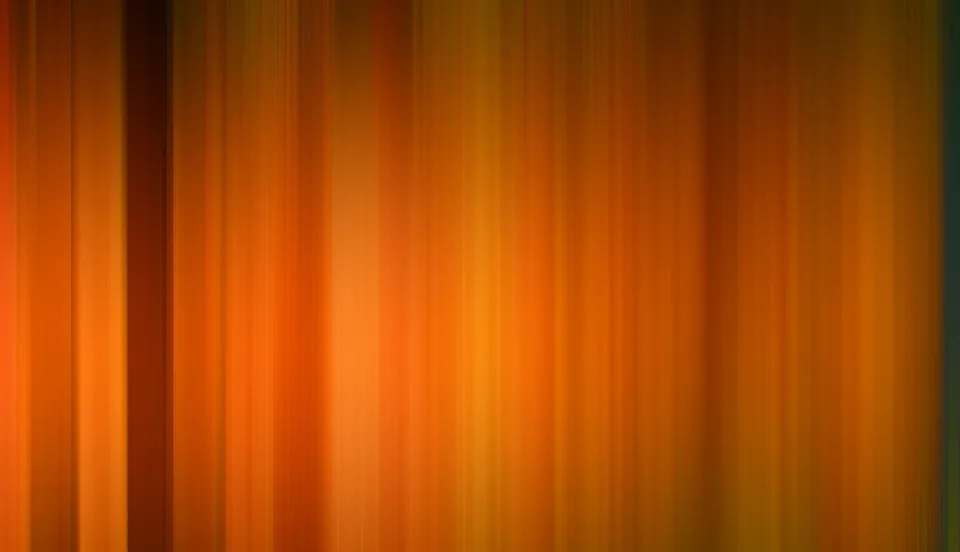 Vertikal verwischte Streifen in Orange, Gelb und Braun, die von links nach rechts ineinander übergehen, am linken Rand ein dunklerer Streifen.