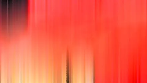 Abstrakte, vertikal verwischte Streifen in Rot, Orange und Gelb, oben links dunkel.
