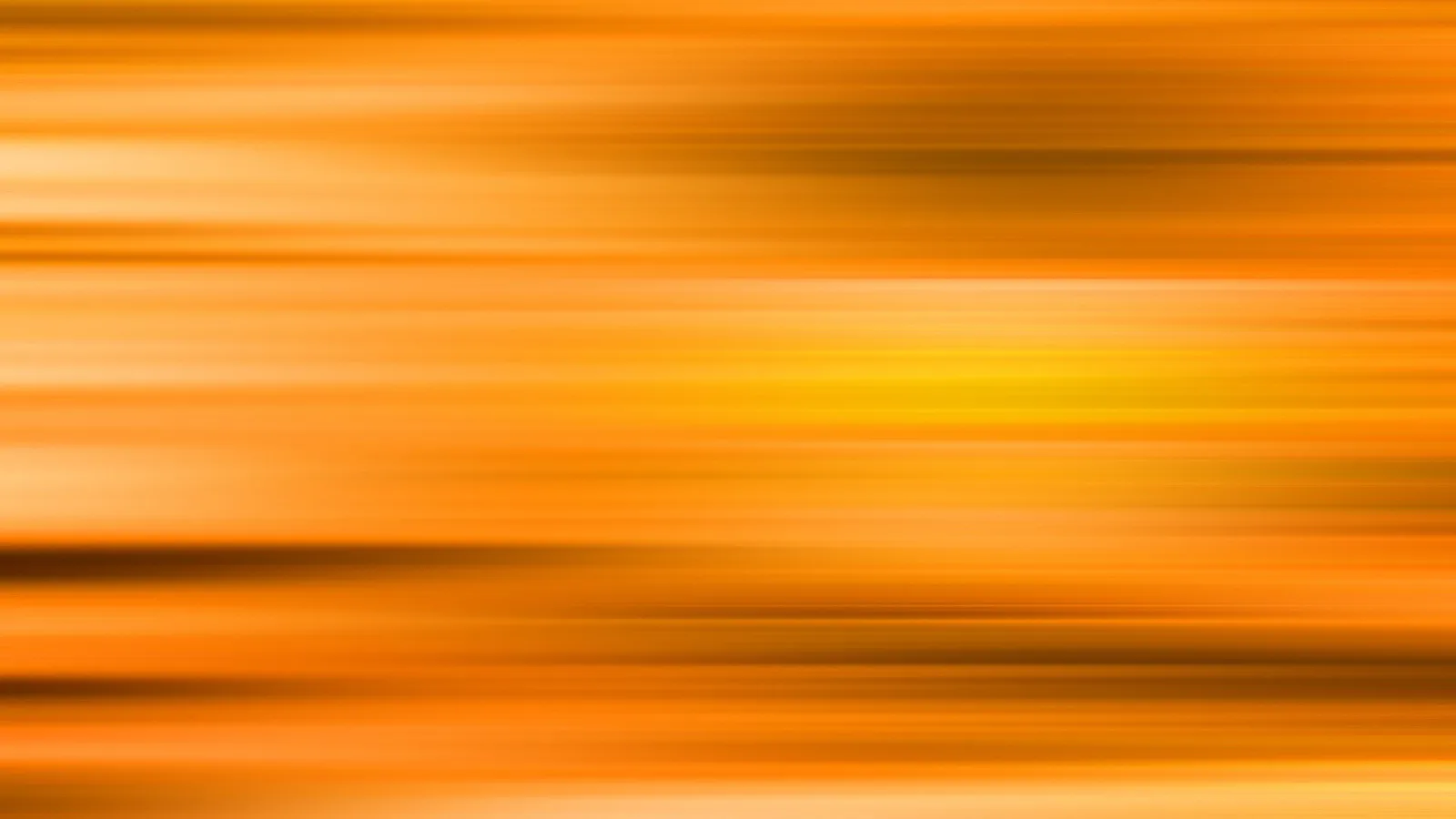 Horizontal verwischte Streifen in Orange, Gelb und Braun, die hellste Stelle liegt rechts der Mitte.