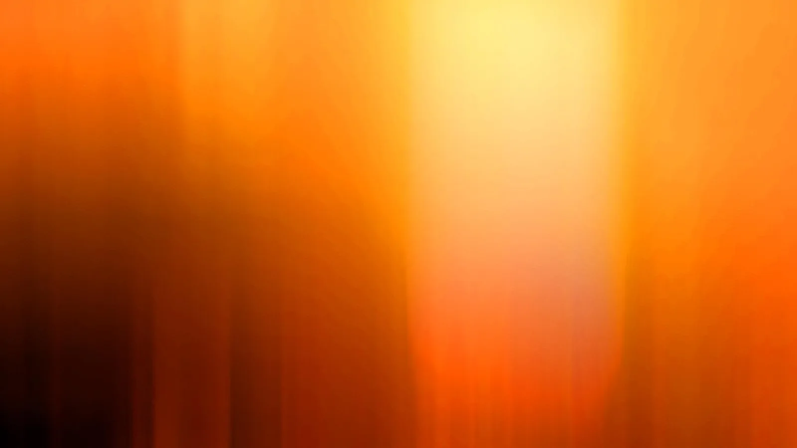 Abstrakte, vertikal verwischte Farbverläufe in Orange, Gelb und Dunkelbraun, mit einem hellen Lichtfeld oben in der Mitte.