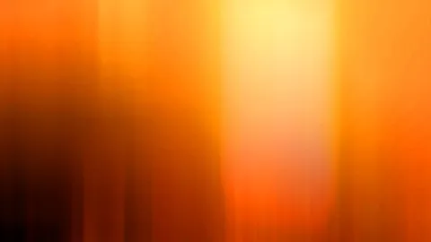 Abstrakte, vertikal verwischte Farbverläufe in Orange, Gelb und Dunkelbraun, mit einem hellen Lichtfeld oben in der Mitte.