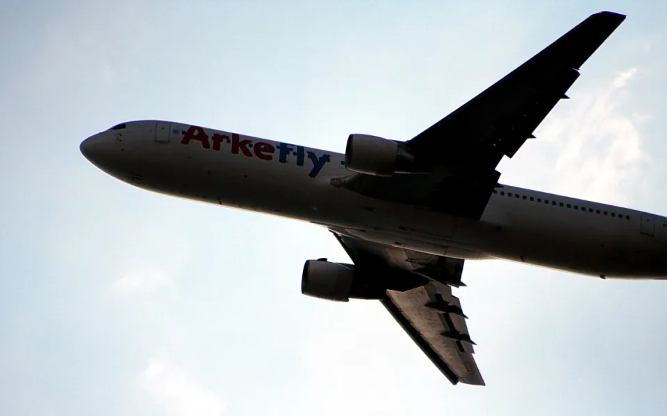 Passagierflugzeug der Airline Arkefly mit Triebwerken und Flügel vor hellem Himmel, von unten fotografiert