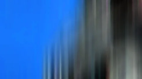 Stark verwischte Aufnahme mit einer großen blauen Fläche links und grauen, dunklen vertikalen Streifen rechts.