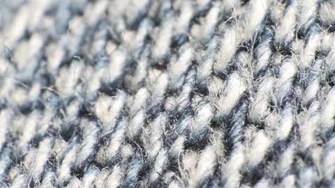 Nahaufnahme eines grau-blauen Stoffs mit diagonalem Gewebemuster und feinen losen Fasern.