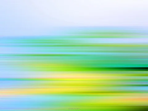 Horizontal verwischte Streifen in Grün, Gelb und Hellblau, oben in einen weißlich blauen Himmel übergehend.