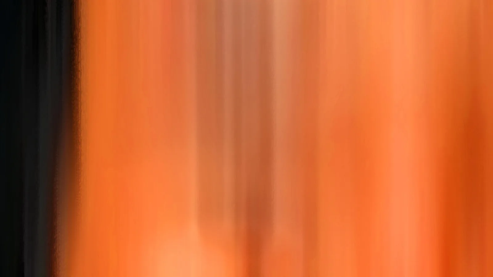 Abstrakte, senkrecht verwischte Farbflächen in Orange, links begrenzt durch einen dunklen Streifen.