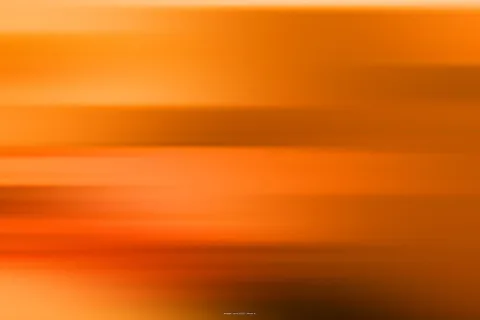 Horizontal verwischte Streifen in Orange, Gelb und Dunkelbraun, die von hell oben nach dunkel unten verlaufen.