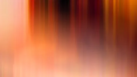 Abstrakte vertikale Bewegungsunschärfe in Orange, Rot und Pink mit einem dunklen Bereich in der oberen Bildmitte.