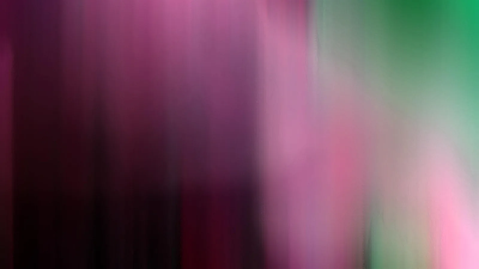 Verschwommene vertikale Streifen in Magenta, Pink und Grün, links dunkler, rechts oben grün.