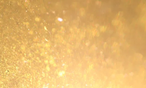 Goldgelber Hintergrund aus glitzernden, unscharfen Lichtpunkten mit warmem Glanz.